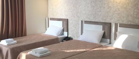 A hotel room with two beds, each with a brown bedspread and white pillows, and a wooden headboard. There are two bedside tables with lamps and a telephone.