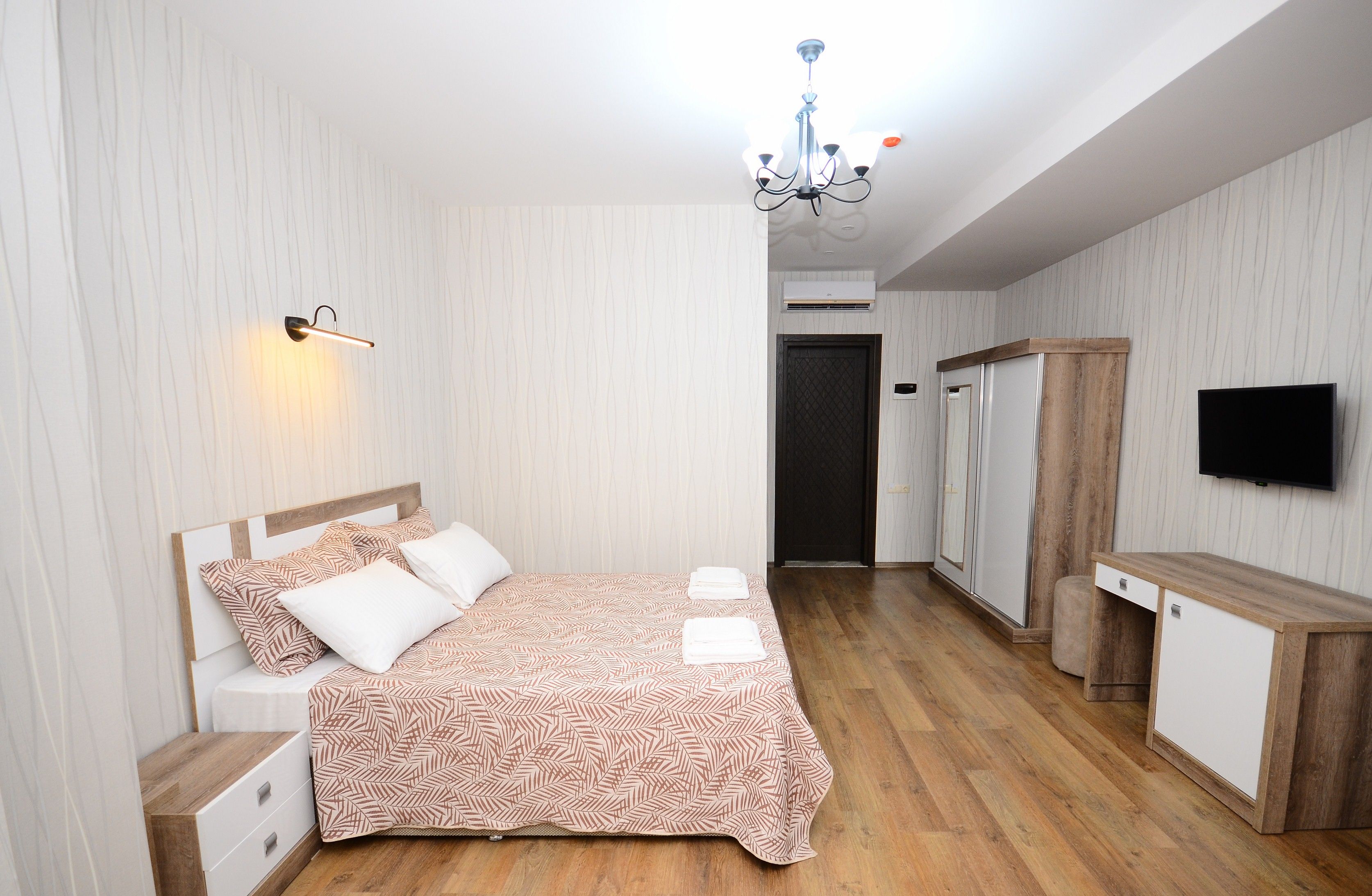 Een slaapkamer met een bed, nachtkastjes, een kledingkast, een bureau en een televisie.