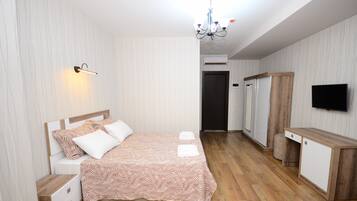 Een slaapkamer met een bed, nachtkastjes, een kledingkast, een bureau en een televisie.