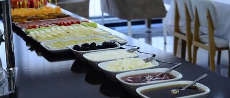 A buffet table with various food items and condiments.