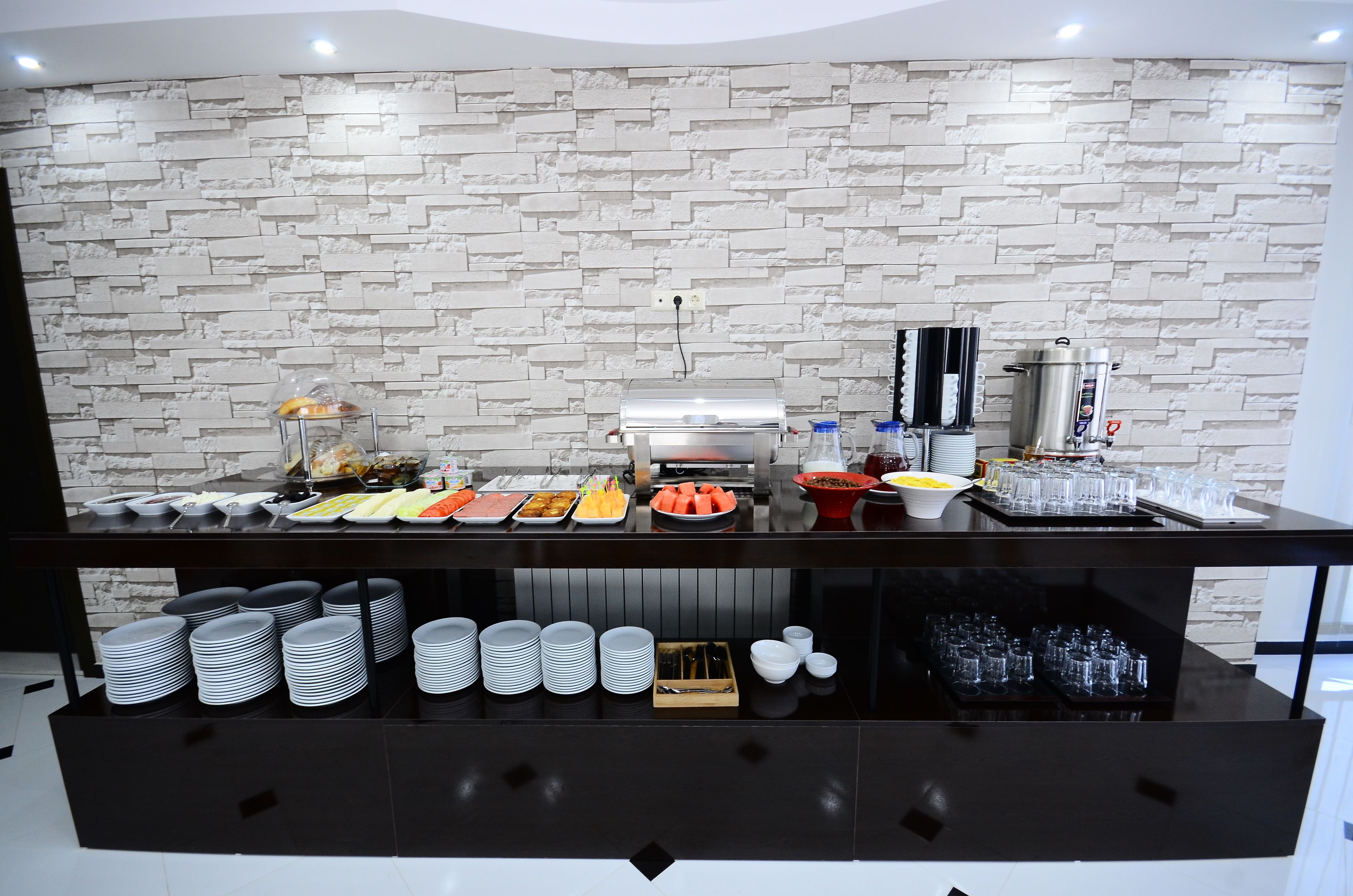 Un buffet proposant une variété de plats et de boissons, un grill, ainsi que des assiettes et des verres disposés avec soin.