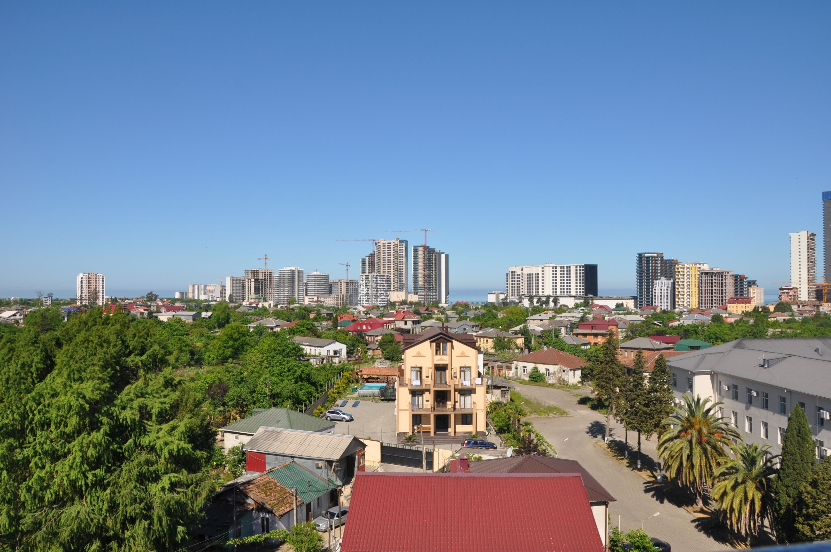 A cityscape with a mix of residential and commercial buildings, including high-rise structures and a prominent yellow building in the foreground.
