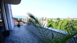 Un balcon offrant une vue sur le paysage urbain, avec ses bâtiments et sa végétation.