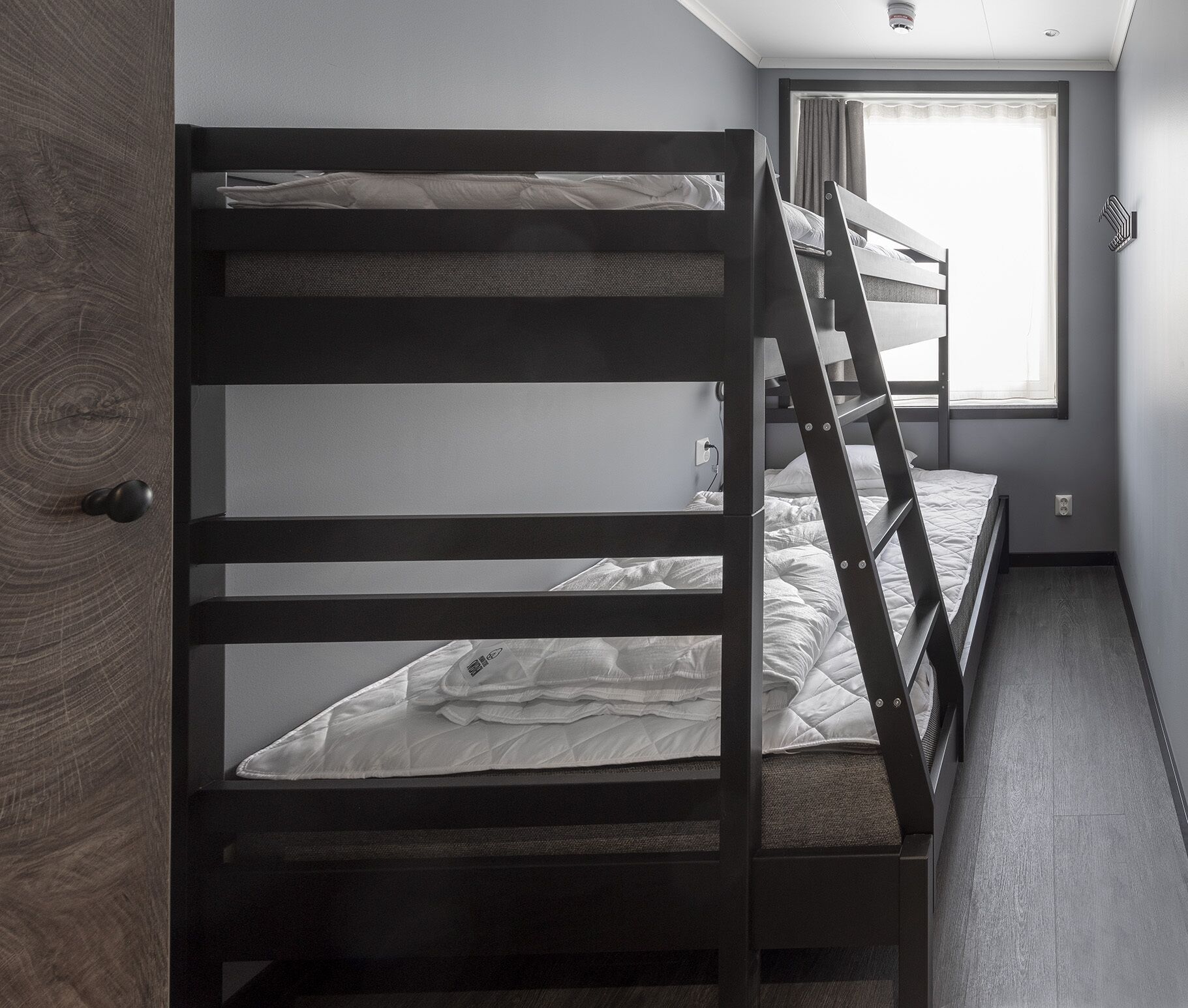 A bunk bed room with a window and a door.