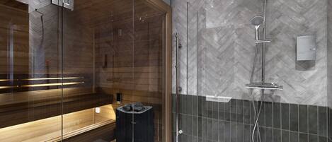 Ein modernes Badezimmer mit einer gläsernen Sauna, einer Duschkabine mit Zickzack-Fliesenmuster und einer Sitzbank mit Handtuchhalter.