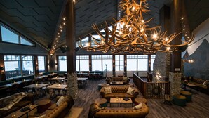 A spacious indoor area with leather seating, a large chandelier, and a view of the outdoors through large windows. - Mountain Lodge (Salen)
