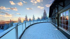 A snow-covered deck with a curved railing overlooking a forest of trees. - Mountain Lodge (Salen)