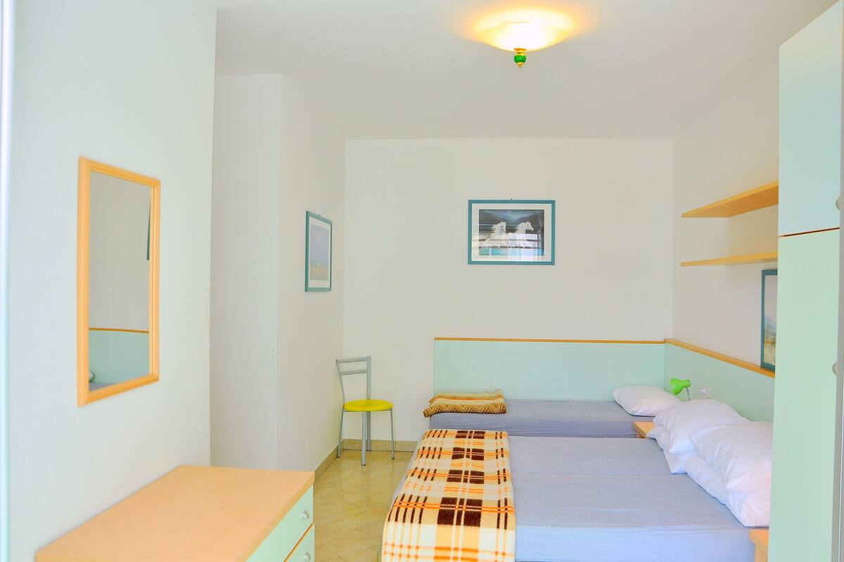 Una camera da letto con due letti, una sedia, una scrivania e uno specchio.