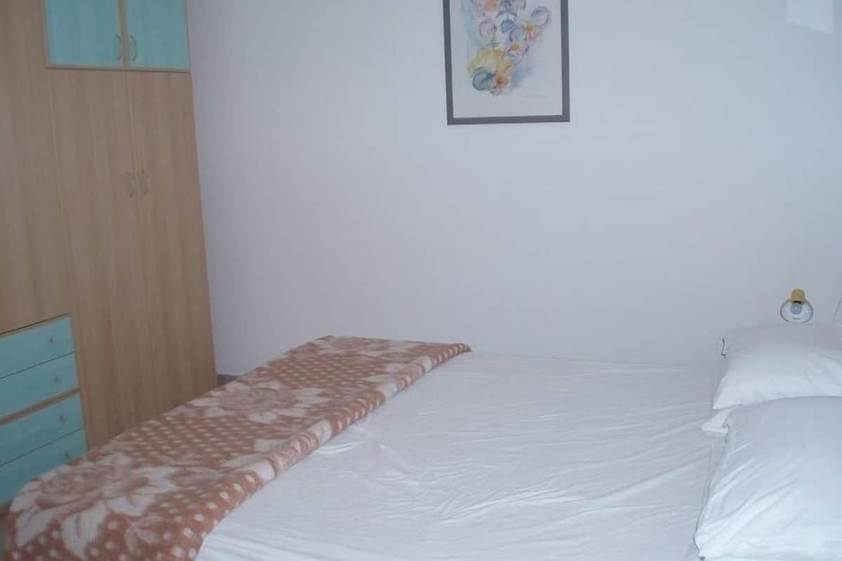 Una camera da letto con un letto, un'armadio in legno e un quadro appeso al muro.