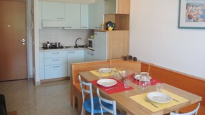 Una cocina compacta con armarios azul claro, una mesa de madera dispuesta para comer y un refrigerador pequeño.
