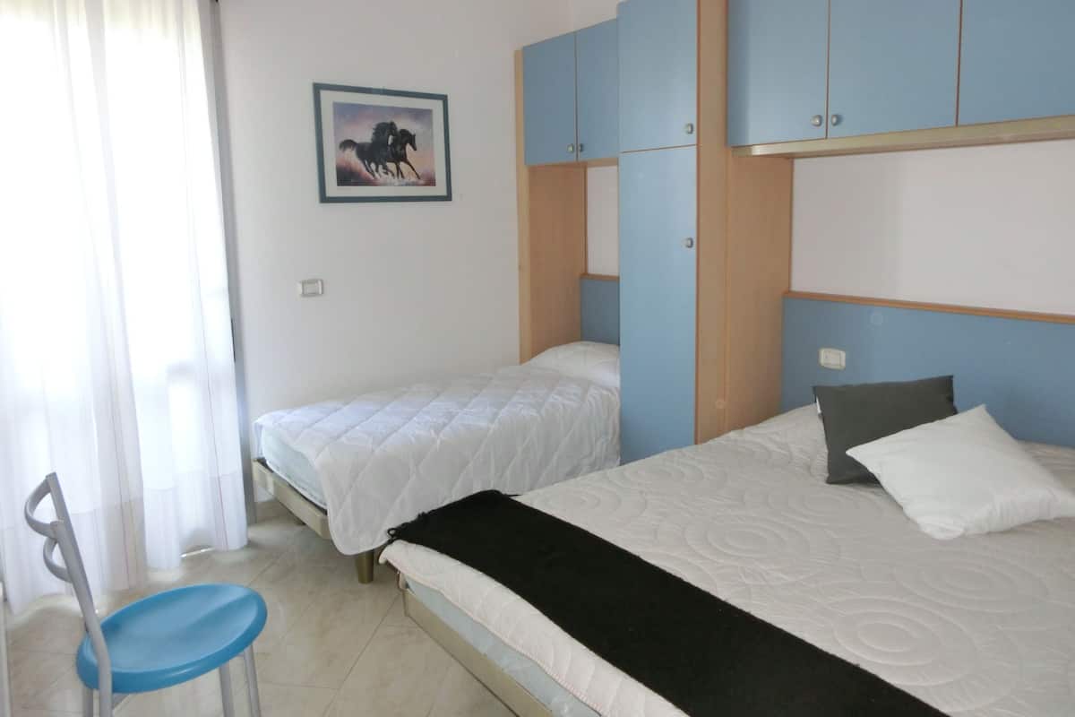 Una camera d'albergo con due letti, una poltrona e un quadro appeso al muro.