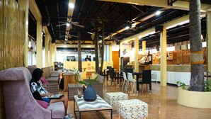 A spacious indoor area with seating, a reception desk, and a bar area. - Maya Playa (Panglao)