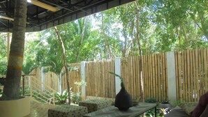 An outdoor patio area with a bamboo fence, tiled flooring, and seating arrangements. - Maya Playa (Panglao)