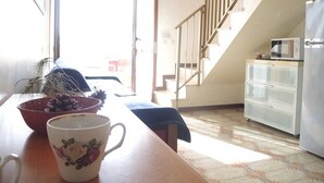 A kitchen with a wooden table, a microwave, and a refrigerator.