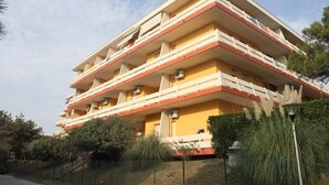 A multi-story building with balconies, air conditioning units, and a fence.
