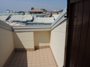 A small, enclosed balcony with tiled flooring and a view of surrounding buildings. - Condominio Carina (San Michele al Tagliamento)