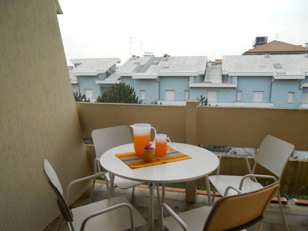 Ein Balkon mit einem runden Tisch, vier Stühlen, zwei Karaffen mit Orangensaft und einer kleinen Schüssel.