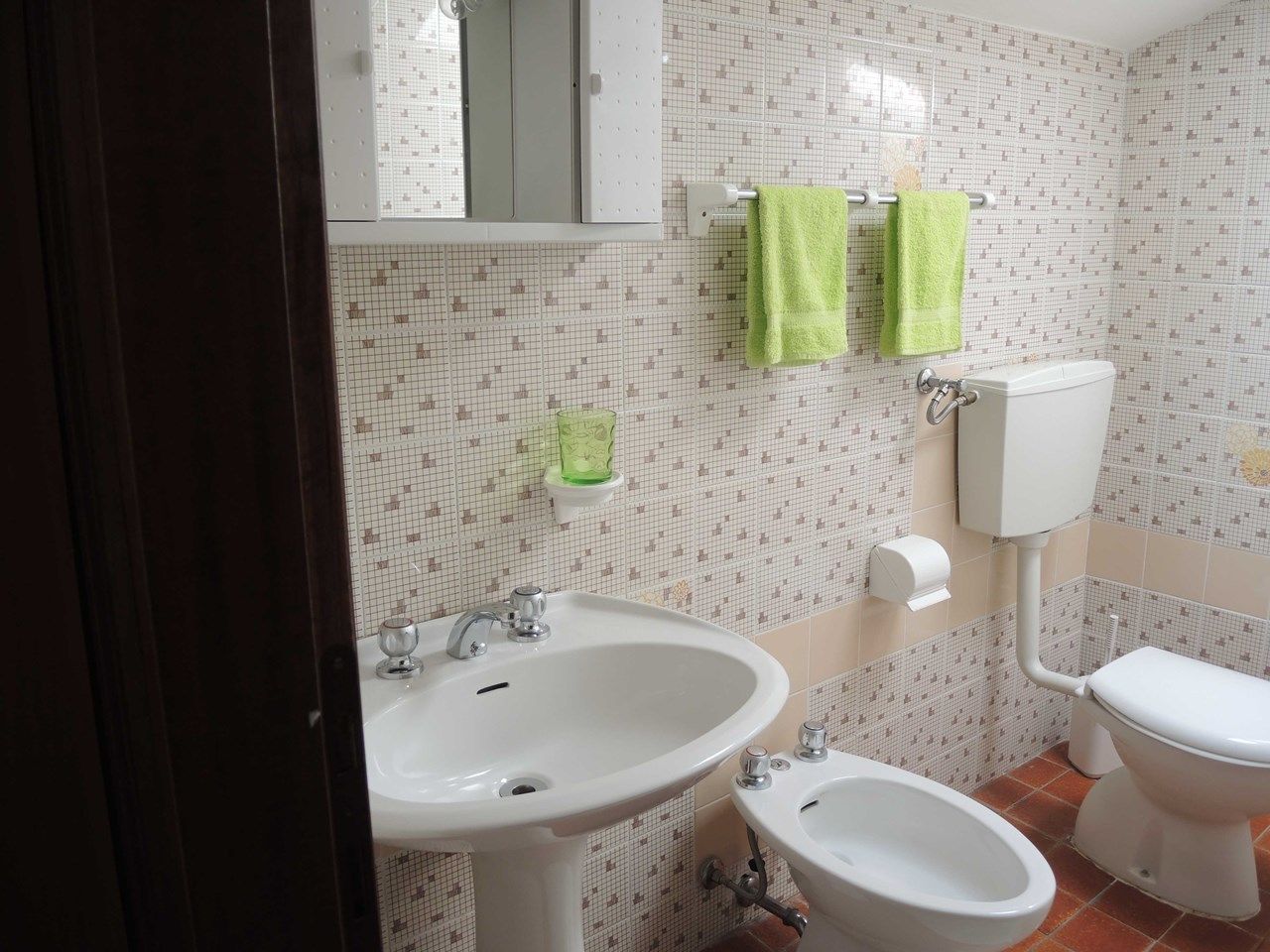 A bathroom with a sink, bidet, toilet, and a mirror.