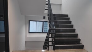 A staircase with a black railing leading to a landing with a window.