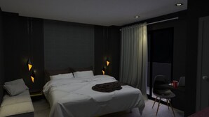A modern bedroom with a large bed, two bedside tables, a chair, and a desk with a laptop.