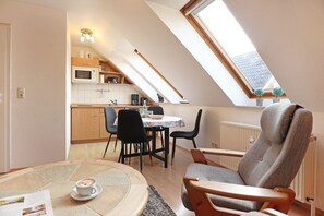 En hyggelig loftlejlighed med spiseplads, et køkken og et stort vindue, der giver masser af naturligt lys.