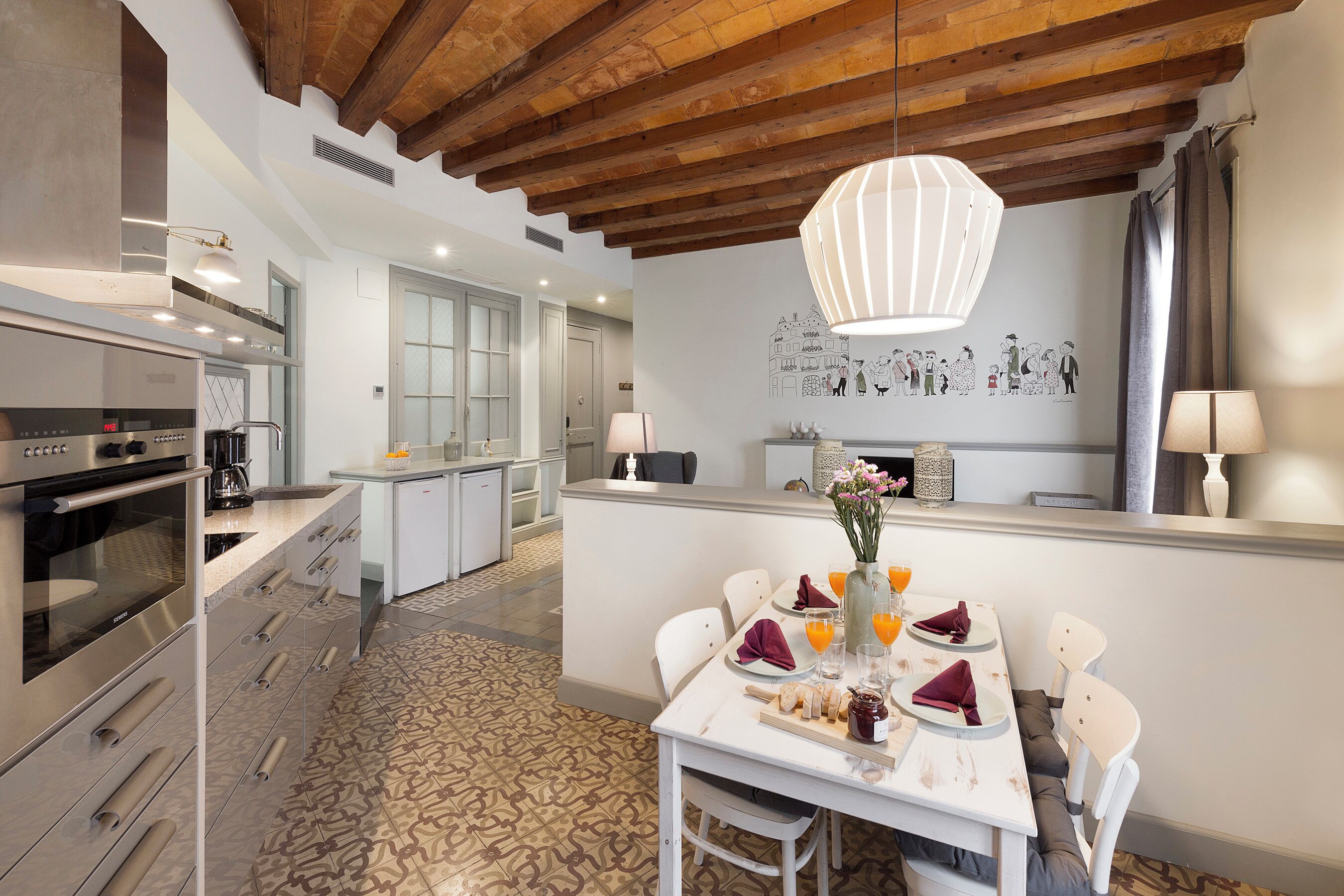 Una cucina moderna con elettrodomestici integrati, un'area pranzo con tavolo apparecchiato per quattro persone e un murale decorativo.