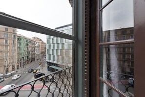A view from a window overlooking a street with buildings, a bicycle, and a car. - Habitat Apartments Alaia (Barcelona)