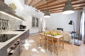 A modern kitchen with a central island, wooden dining table, and pendant lighting. - Habitat Apartments Alaia (Barcelona)