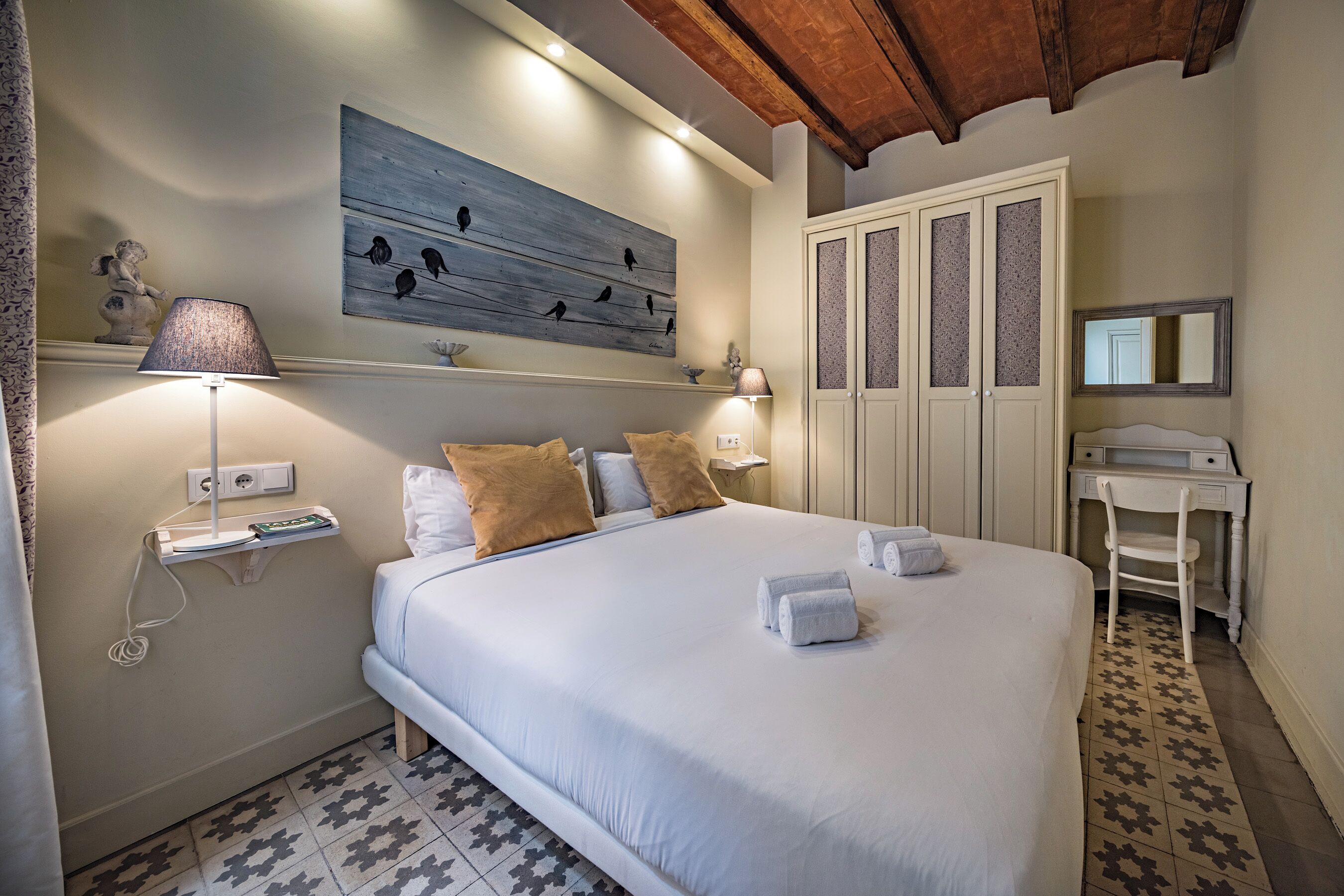 Une chambre bien rangée, avec un lit, des lampes de chevet, un bureau et une armoire.