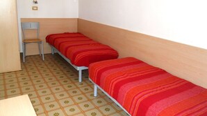 A small room with two single beds, a chair, and a wooden door. - Ville Schiera (San Michele al Tagliamento)