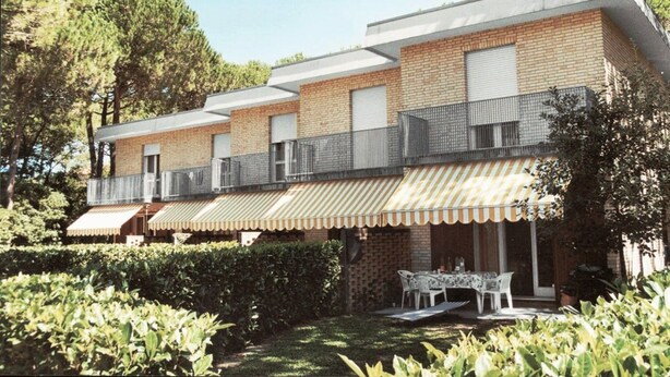 A modern building with a brick facade, multiple balconies, and a covered outdoor seating area. - Ville Schiera (San Michele al Tagliamento)