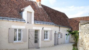 A building with a gravel driveway, multiple doors, and a stone wall.