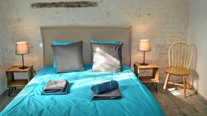 A bedroom with a bed, two bedside tables, a chair, and a lamp on each table.