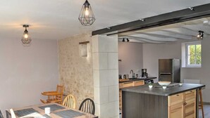 A modern kitchen with a central island, wooden cabinets, and pendant lighting.