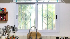A kitchen with a double sink, a window with decorative iron bars, and a wooden spice rack. - Charming casa, 1 block to the beach- safe, quiet, excellent wifi, AC (Punta de Mita)