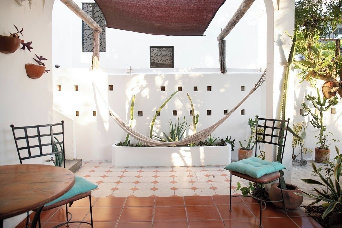 A patio with a hammock, two chairs, and potted plants.