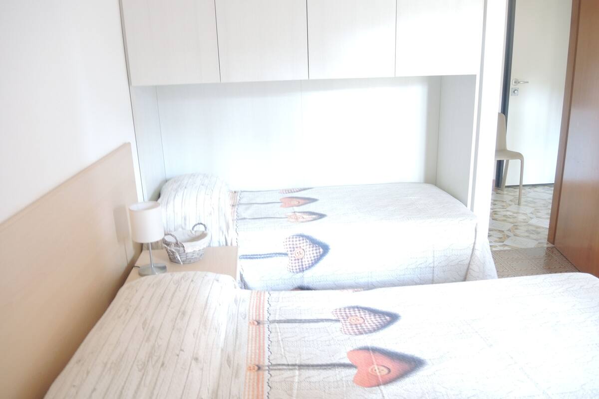 Une chambre avec deux lits, une table de chevet, une lampe et une chaise.
