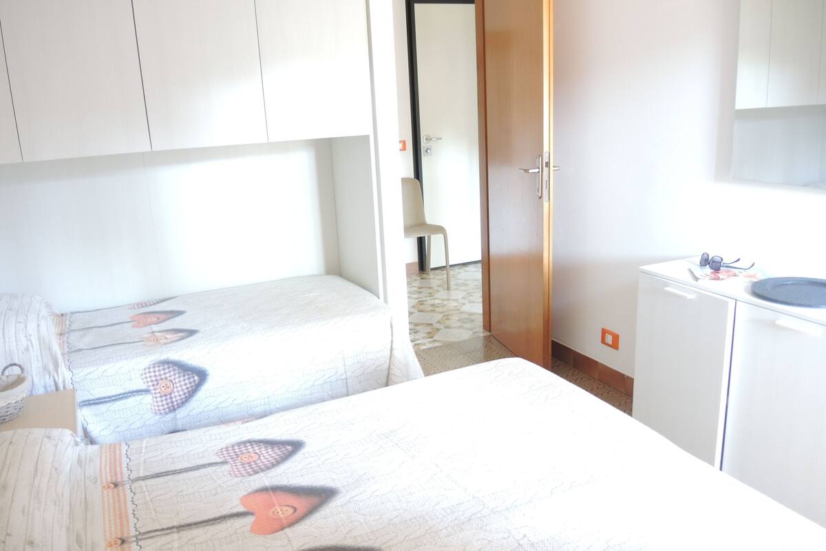 Une chambre avec deux lits, une petite table et un placard.