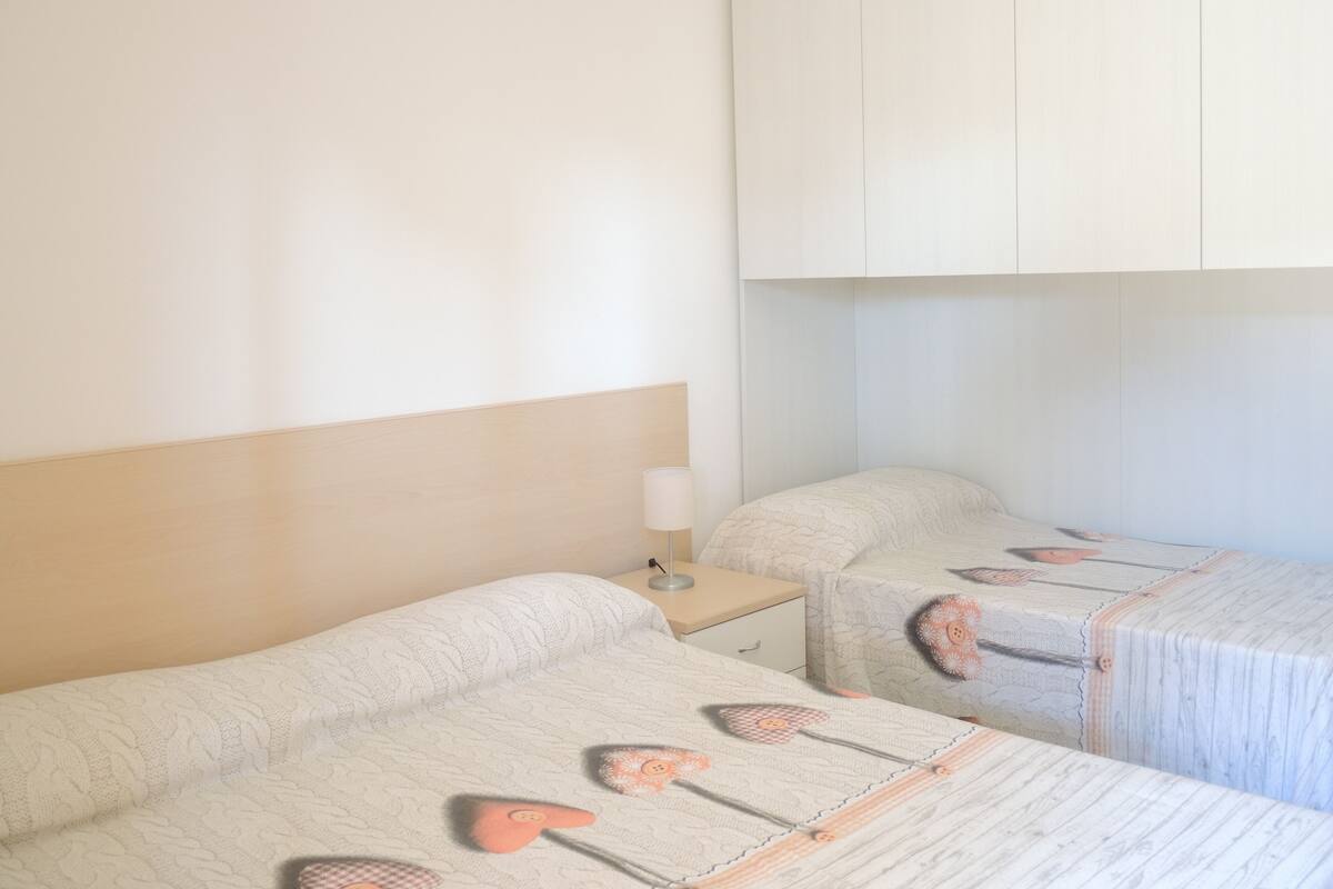 Une chambre d’hôtel avec deux lits, chacun doté d’une tête de lit et d’une table de chevet.