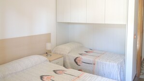 Une chambre avec deux lits simples, une table de chevet avec une lampe et une armoire.
