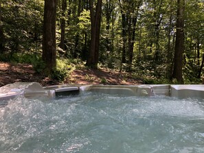 A hot tub in a forested area with trees and greenery in the background. - Adventure awaits right out the back door, Discover tranquility in PA woodlands (Ringtown)