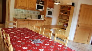 Una cocina con armarios de madera, un microondas, un horno y una mesa de comedor con mantel rojo.