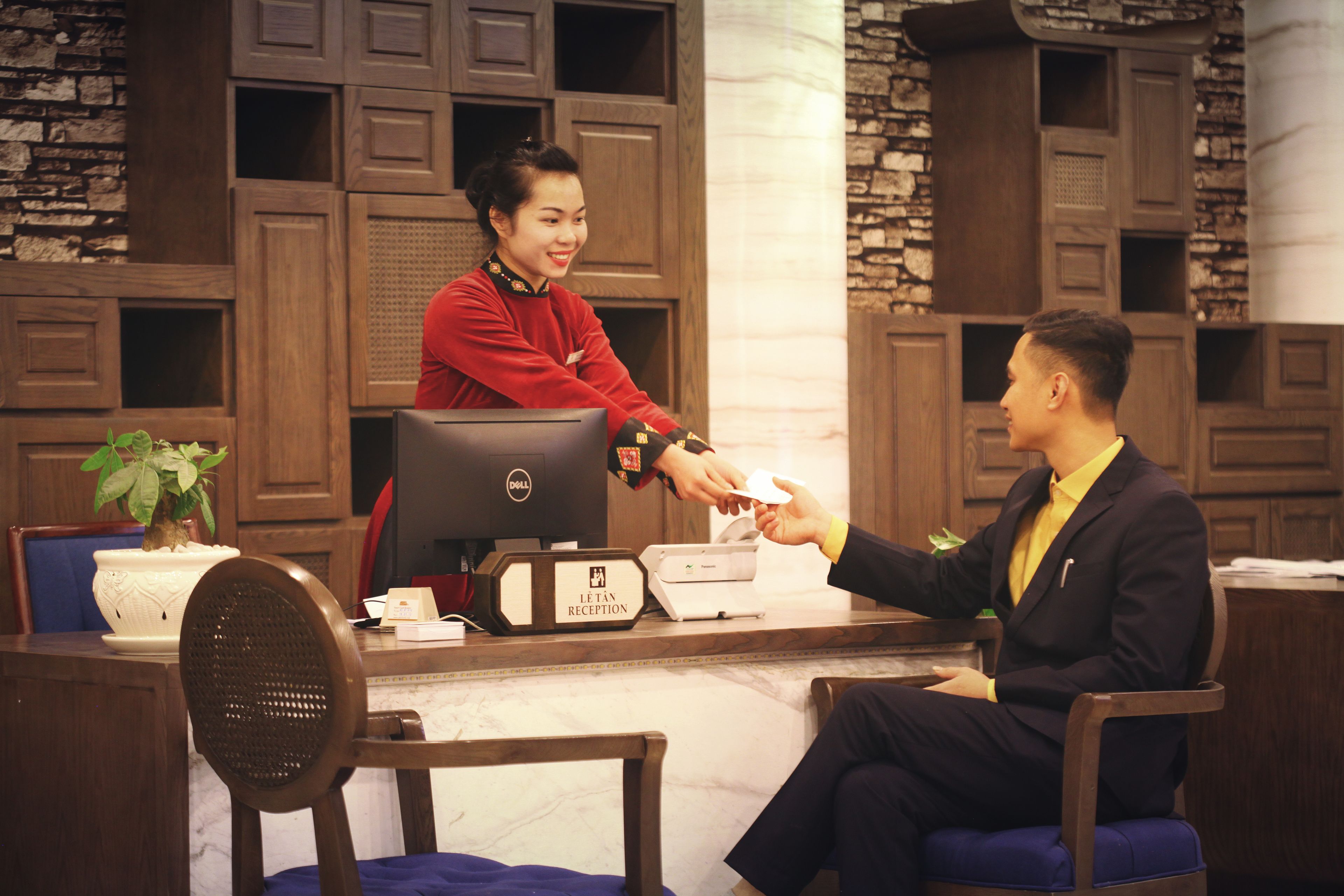 A reception desk with a computer, a plant, and a printer.