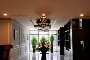 Un vestíbulo de hotel con un cartel para el Restaurante Lotus, obras de arte enmarcadas en las paredes y plantas en macetas.