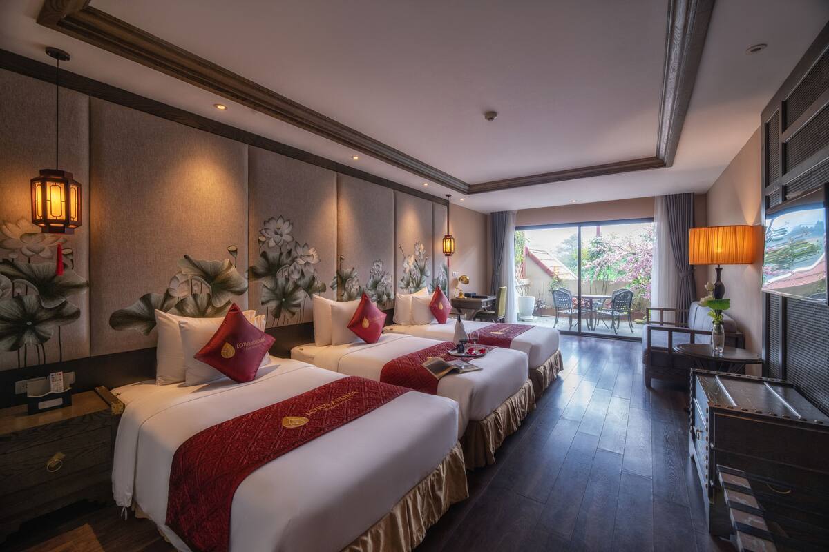 Una habitación de hotel con tres camas, una zona de estar y vistas al exterior.
