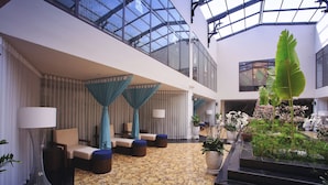 Un hall d’entrée spacieux, doté d’un plafond haut, de grandes fenêtres et d’un espace salon central agrémenté d’un tapis à motifs.