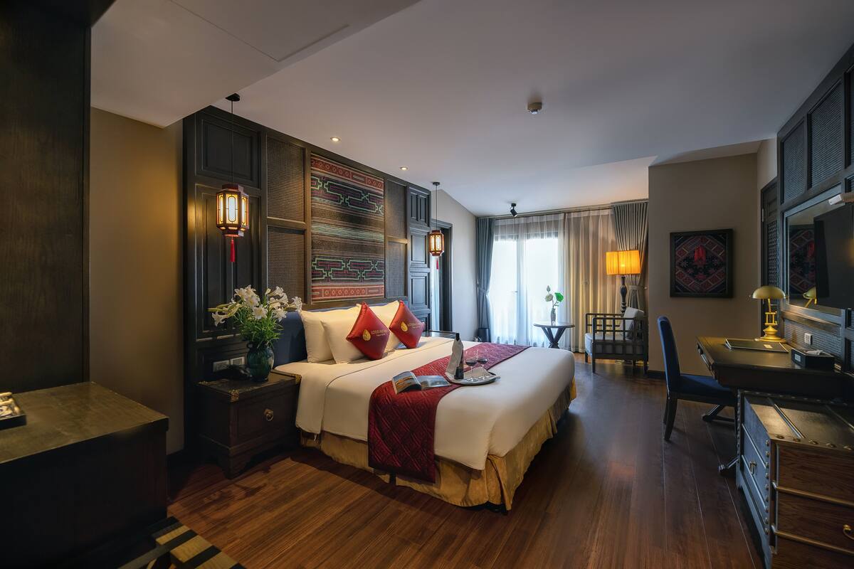 Una habitación de hotel con una cama grande, mesitas de noche, un escritorio y una silla.