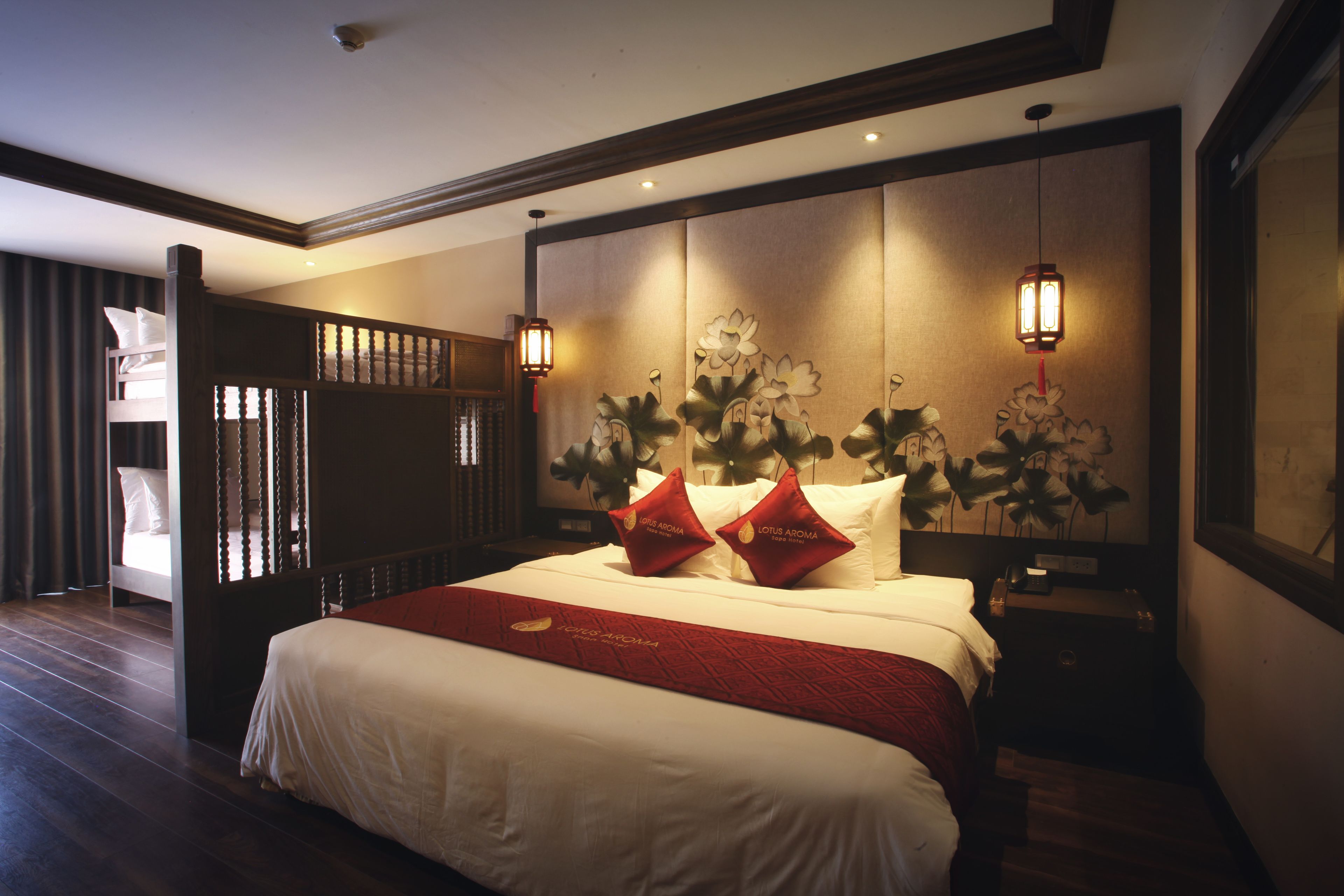 A hotel room with a large bed, wooden headboard, and two wall-mounted lamps.