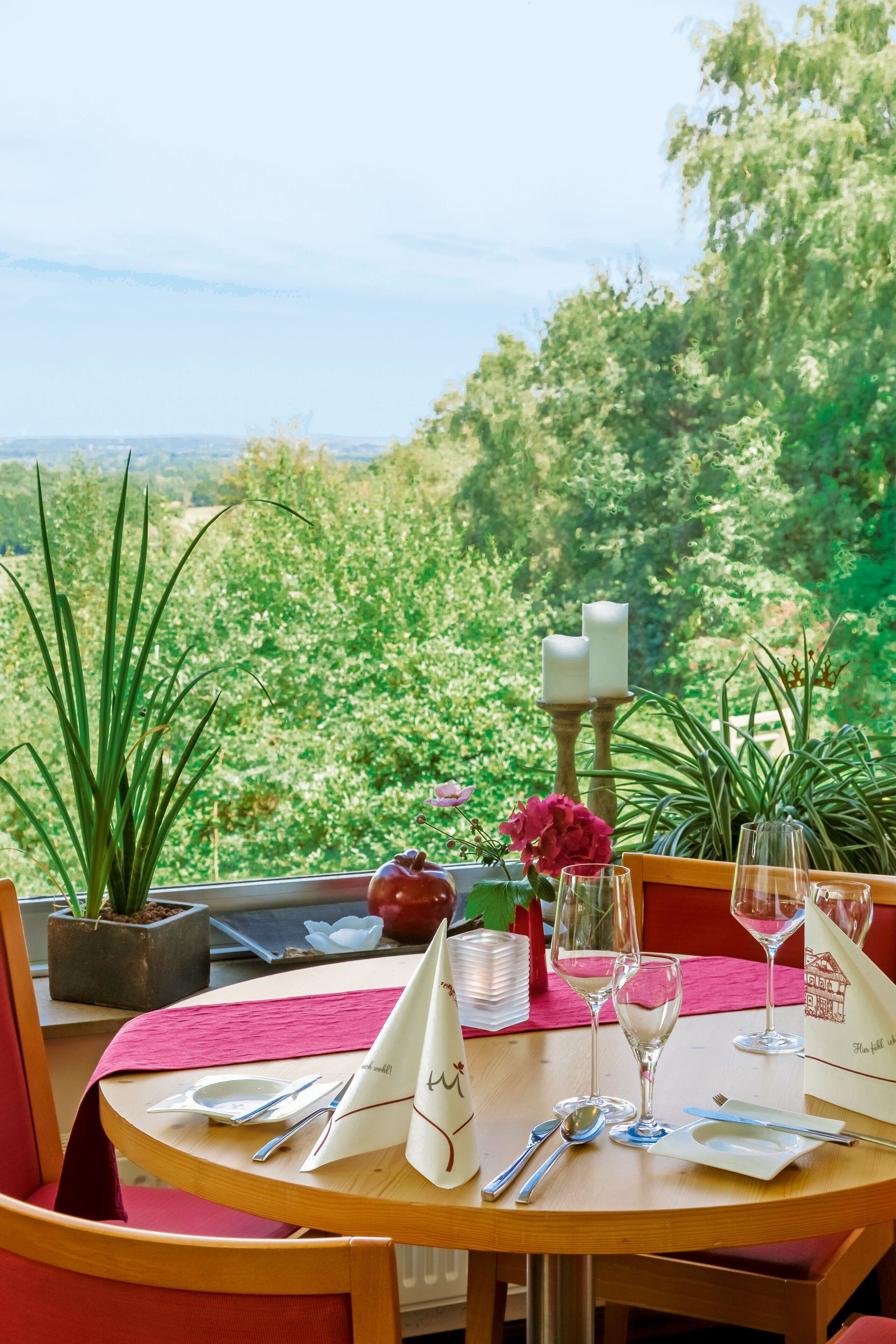 A table set for dining with a view of a lush garden and distant landscape.