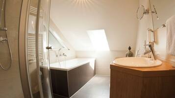 A modern bathroom with a glass-enclosed shower, a freestanding bathtub, and a vanity with a mirror.
